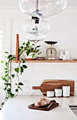 L-shaped kitchen counter below houseplants and vintage scales on shelf