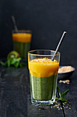 A layered, green-and-yellow smoothie with lamb's lettuce, kiwi and mango