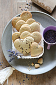 Heart-shaped, gluten-free lavender shortbread biscuits in a cardboard dish
