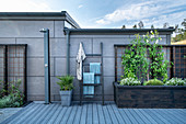 Outdoor shower, towel rack and raised beds against outside wall of house