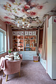 Girl's bedroom decorated in pink with floral wallpaper on ceiling, cubby bed and bookcase