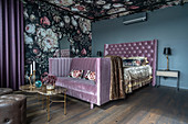 Double bed and bedroom sofa against dramatic floral wallpaper in bedroom