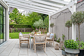Dining table and rattan chairs on terrace with pergola