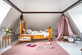 Antique wooden bed and play area with canopy in girl's bedroom
