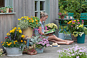 Colourful summer terrace with perennials and summer flowers, woman enjoys the summer