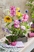 Sträuße mit Gladiolen, Sonnenblume, Kugeldistel, Waldrebe, Dahlie, Fenchelblüte und Wiesenkümmel in Holzkistchen