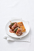 Meat and sausage skewers with sage, served with grilled polenta
