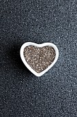 Black chia seeds in heart shaped dish