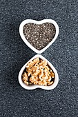 Black chia seeds and walnuts in heart shaped dish