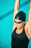 Female swimmer stretching on poolside