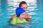Boy in swimming pool with mother