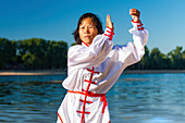 Women practicing tai chi by lake