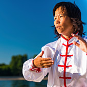 Women practicing tai chi by lake