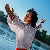 Women practicing tai chi by lake