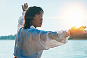 Women practicing tai chi by lake