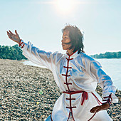 Women practicing tai chi by lake