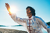 Women practicing tai chi by lake