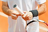 Player putting new grip tape on tennis racket