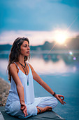 Woman meditating by a lake