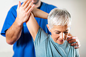 Physical therapist examining patient's shoulder