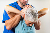 Physical therapist stretching senior woman's neck