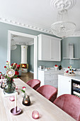 View across dining table into white fitted kitchen