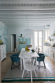 Dining area in white country-house kitchen with wood-beamed ceiling