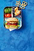 Lunchbox with mini cheeseburger subs, fresh fruits and vegetable