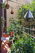 Striped folding furniture, plants, nesting boxes and bird feeder on urban balcony