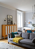 Sofa used as partition in open-plan interior with kitchen-dining area