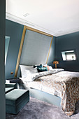 Bed with high, upholstered headboard on sloping wall in elegant bedroom