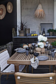 Set table in natural shades on terrace with exotic accessories