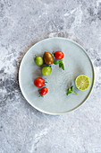 Verschiedene Tomaten und Limettenhälfte auf Teller