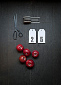 Ribbon, numbered card, red apples and scissors on dark surface