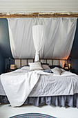 Grey and white double bed with ruffles and DIY canopy under sloping ceiling