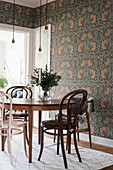 Bistro chairs at round table in dining room with Arts and Crafts wallpaper