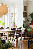 Spoke-back chairs around dining table and houseplants in interior