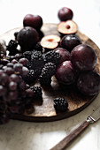 Autumn fruits: red grapes, blackberries and plums on a wooden board