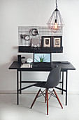 Schwarzer Tisch mit Designerstuhl als Arbeitsplatz vor Wandaufhängung mit Aufbewahrungsfunktion