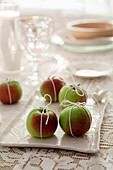 Äpfel mit Bändern umwickelt als weihnachtliche Tischdekoration