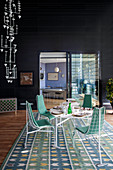 Wohnraum in Penthouse mit schwarzen Wänden und Essbereich mit weißen Metallmöbeln auf blau-grünem Vintage-Teppich