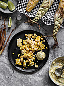 Shaved mexican street corn with herbed butter scoop on the plate.