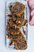 Fig bread recipe with banana, fresh figs and walnuts sliced on a rectangular plate.