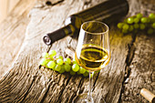 Glas Weißwein, grüne Trauben und Weinflasche