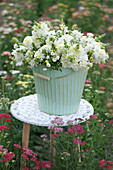 A white bouquet of dahlias, snapdragons, and bergamot in a tin bucket