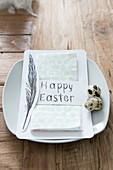 Napkin in paper bag with Easter greeting and painted feather