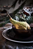 Place setting festively decorated with pear and sprigs of eucalyptus and pine