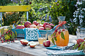 Tray with freshly picked apples, decanters and glasses with apple juice, crab apples as decoration