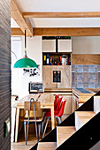 Dining table and green pendant lamp in open-plan kitchen with furnishings made from recycled materials