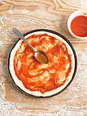 Pizzateig mit Tomatensauce bestreichen